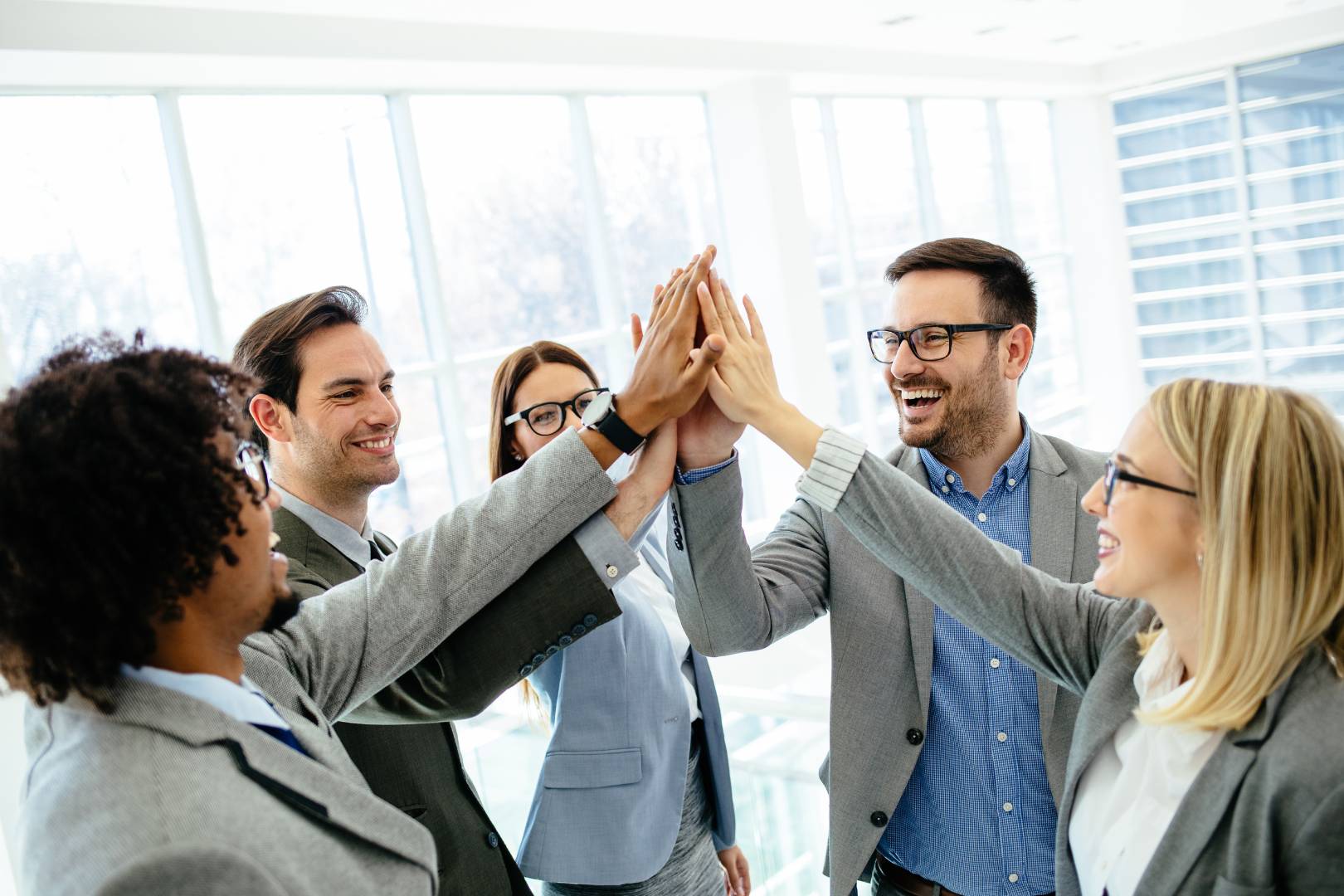 Upward Arrow Branding and Marketing Agency Team hi-fiving each other in celebration of shared success due to Upward Arrow's help with branding, marketing and business consulting.